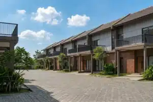 Kawasan rumah Tipe Toba Serpong Lakeville tampak dari sisi jalan cluster – lingkungan asri dengan pohon tropis dan paving block